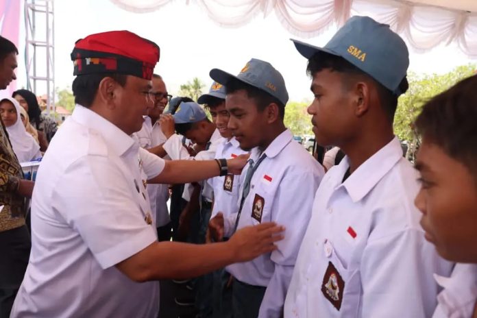 Penjabat (Pj) Gubernur Sulawesi Tenggara (Sultra), Andap Budhi Revianto saat menyerahkan bantuan beasiswa kepada 112 pelajar di Muna Barat. (Foto : Istimewa)